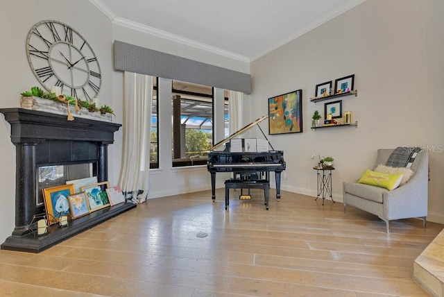 sitting room featuring baseboards, ornamental molding, wood finished floors, and a tile fireplace