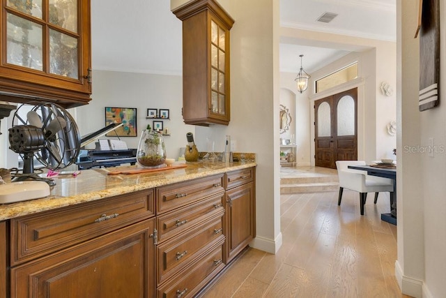 bar area featuring ornamental molding, light wood-style flooring, baseboards, and arched walkways