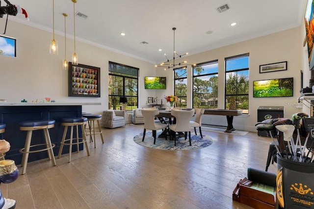 dining room with healthy amount of natural light, crown molding, recessed lighting, light wood finished floors, and a chandelier