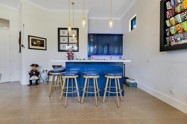 bar featuring ornamental molding, wood finished floors, hanging light fixtures, and baseboards