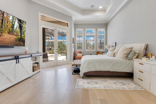 bedroom with access to exterior, a tray ceiling, french doors, light wood finished floors, and crown molding