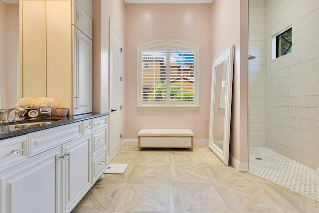 bathroom with walk in shower, vanity, and baseboards