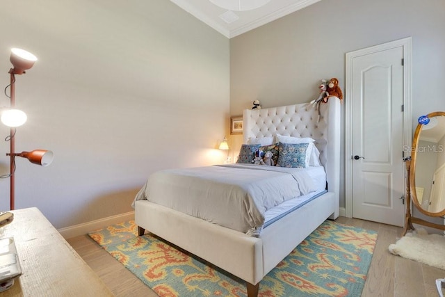 bedroom featuring wood finished floors, ornamental molding, and baseboards