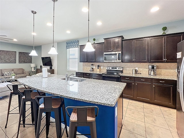 1614 Lima Ave, Kissimmee, FL 34747 - kitchen with stainless steel appliances, a sink, open floor plan, backsplash, and a kitchen bar