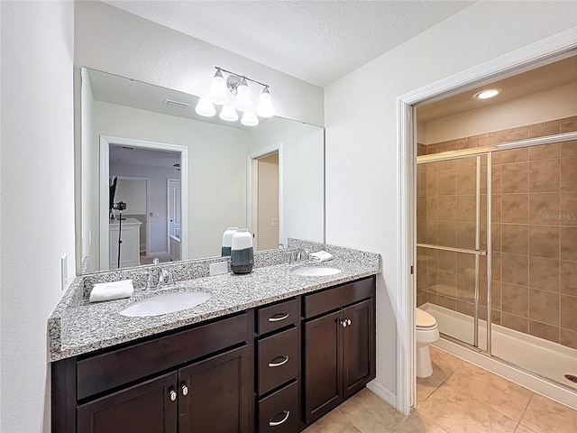 1614 Lima Ave, Kissimmee, FL 34747 - bathroom featuring a stall shower, toilet, double vanity, tile patterned flooring, and a textured ceiling