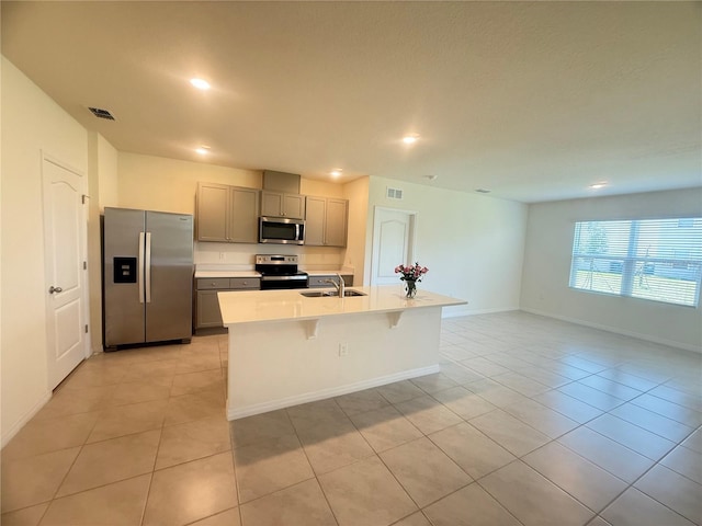 2569 Trinidad Rd, Haines City, FL 33844 - kitchen featuring appliances with stainless steel finishes, gray cabinetry, light tile patterned floors, a sink, and an island with sink