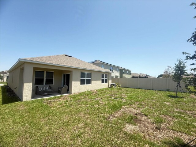 2569 Trinidad Rd, Haines City, FL 33844 - back of property with stucco siding, a patio, a shingled roof, and an outdoor hangout area