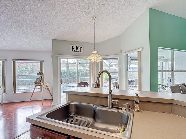 12445 Bohannon Blvd, Orlando, FL 32824 - kitchen with a sink, a textured ceiling, wood finished floors, hanging light fixtures, and light countertops