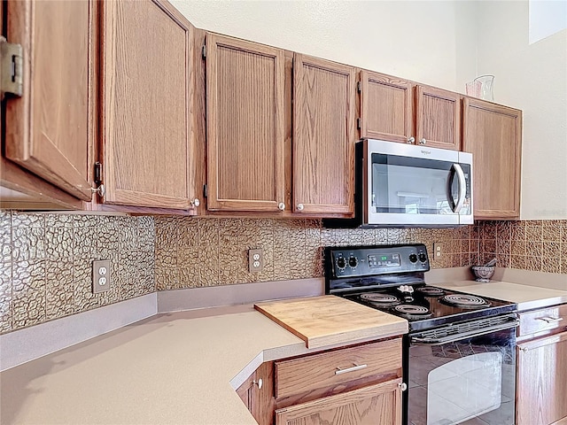 12445 Bohannon Blvd, Orlando, FL 32824 - kitchen featuring stainless steel microwave, electric range, light countertops, and backsplash