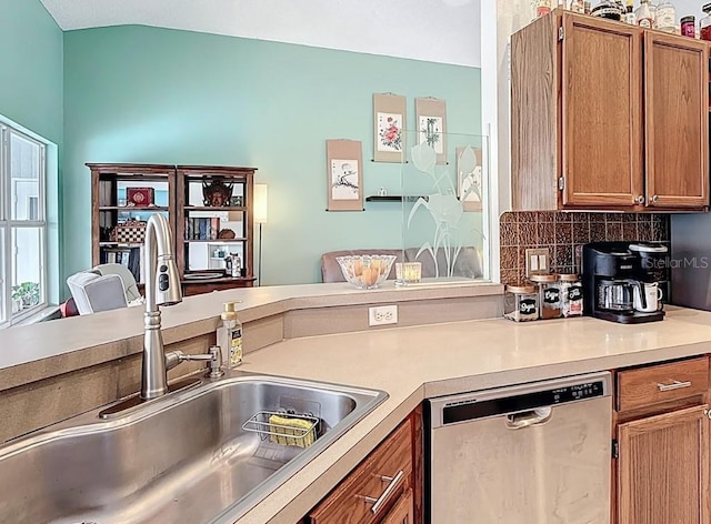 12445 Bohannon Blvd, Orlando, FL 32824 - kitchen with stainless steel dishwasher, a sink, brown cabinetry, and backsplash