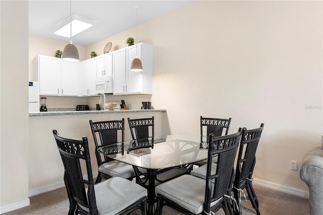 carpeted dining room with baseboards