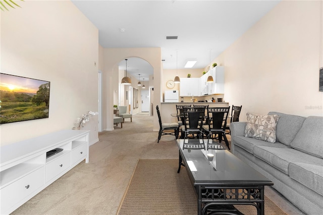 living room with arched walkways and light carpet