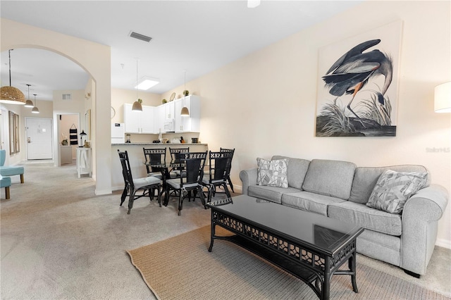 living room with light colored carpet, arched walkways, and baseboards