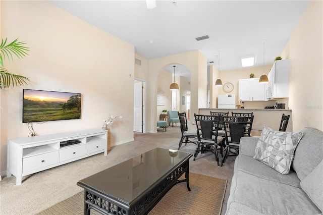 living room with light carpet, arched walkways, and baseboards