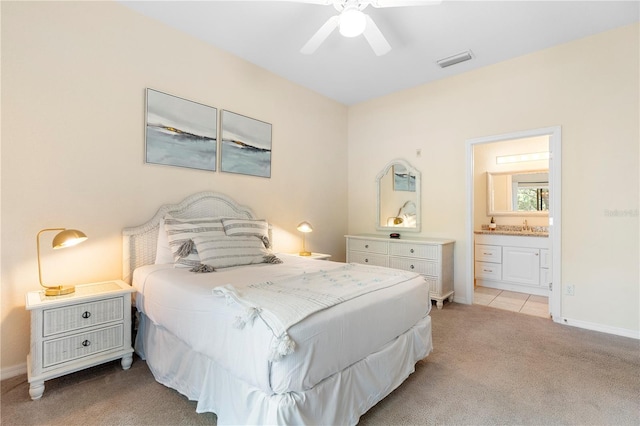 bedroom featuring light colored carpet, ensuite bathroom, baseboards, a sink, and a ceiling fan