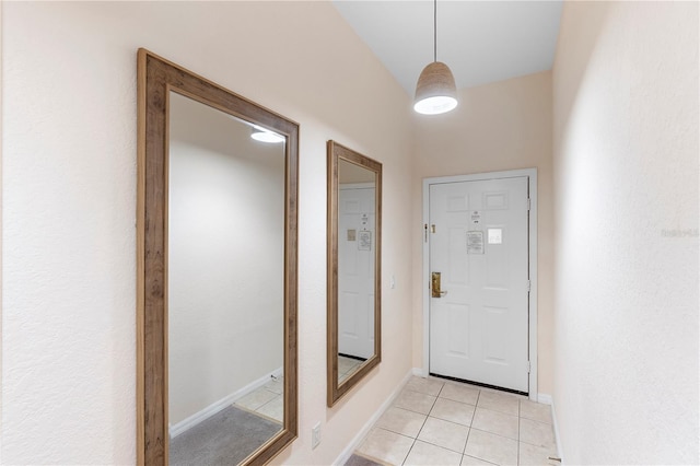 doorway with light tile patterned floors and baseboards