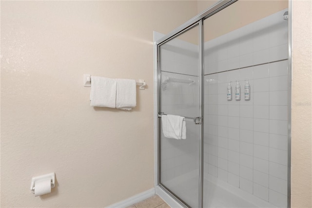 full bathroom featuring a stall shower and baseboards