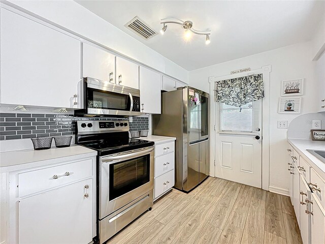 320 S Seminole Ave, Lake Alfred, FL 33850 - kitchen featuring stainless steel appliances, light wood-style flooring, light countertops, and white cabinetry