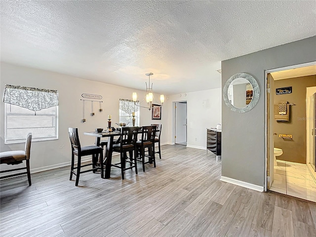 320 S Seminole Ave, Lake Alfred, FL 33850 - dining room featuring light wood-style floors, a textured ceiling, a chandelier, and baseboards