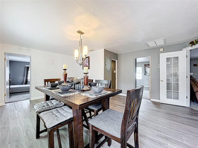320 S Seminole Ave, Lake Alfred, FL 33850 - dining room with light wood-style flooring, a chandelier, a textured ceiling, and baseboards