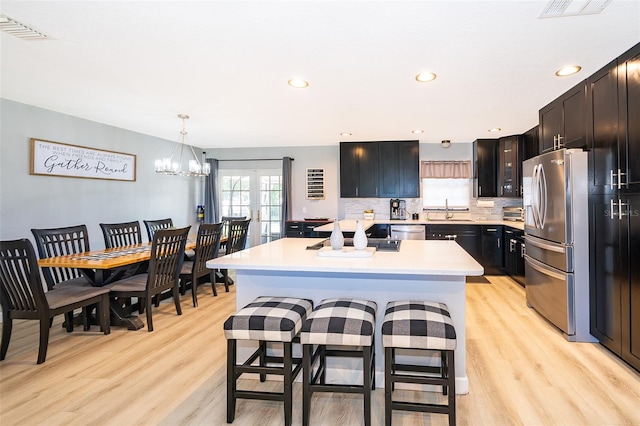 1730 Carolyn Ct, Saint Cloud, FL 34769 - kitchen with stainless steel appliances, a sink, light countertops, light wood-style floors, and a kitchen bar