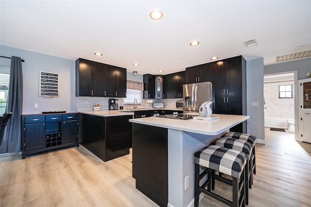 1730 Carolyn Ct, Saint Cloud, FL 34769 - kitchen with stainless steel refrigerator with ice dispenser, light countertops, light wood-type flooring, a breakfast bar area, and recessed lighting