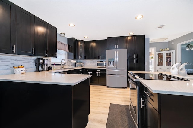 1730 Carolyn Ct, Saint Cloud, FL 34769 - kitchen featuring appliances with stainless steel finishes, a sink, dark cabinets, light wood finished floors, and backsplash
