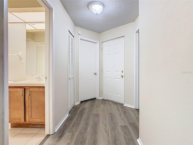 7865 Sugar View Ct Unit 7865, Orlando, FL 32819 - corridor with a textured ceiling, light wood-type flooring, baseboards, and a sink