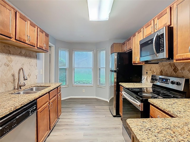 7865 Sugar View Ct Unit 7865, Orlando, FL 32819 - kitchen featuring stainless steel appliances, a sink, decorative backsplash, light stone counters, and light wood-type flooring