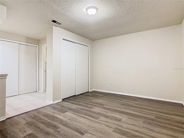 7865 Sugar View Ct Unit 7865, Orlando, FL 32819 - unfurnished bedroom featuring wood finished floors, a textured ceiling, two closets, and baseboards