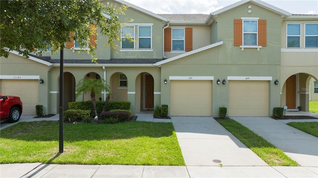3181 Tocoa Cir, Kissimmee, FL 34746 - townhome / multi-family property featuring stucco siding, a front yard, an attached garage, driveway, and covered porch