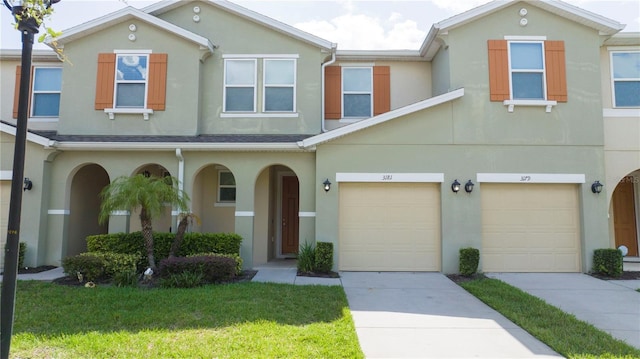 3181 Tocoa Cir, Kissimmee, FL 34746 - townhome / multi-family property with stucco siding, driveway, an attached garage, a front yard, and a porch
