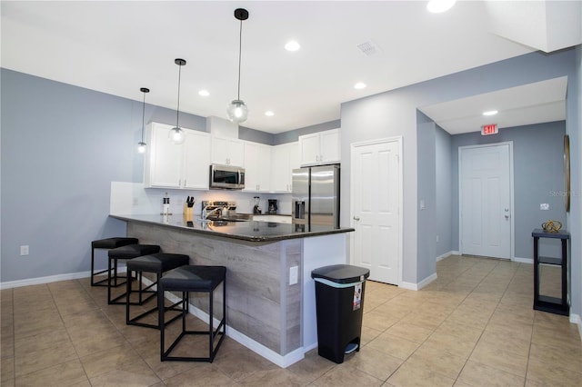 3181 Tocoa Cir, Kissimmee, FL 34746 - kitchen with stainless steel appliances, a peninsula, white cabinets, a breakfast bar, and recessed lighting