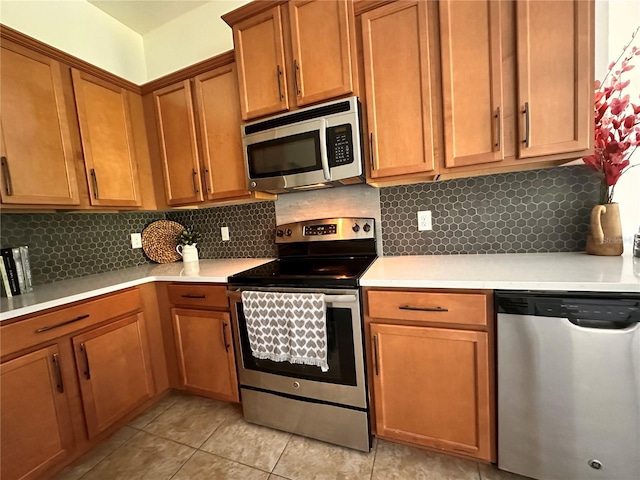 10734 Dawson Lily Way Unit S, Orlando, FL 32832 - kitchen featuring appliances with stainless steel finishes, light countertops, backsplash, light tile patterned flooring, and brown cabinets