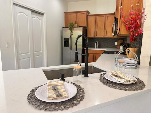 10734 Dawson Lily Way Unit S, Orlando, FL 32832 - kitchen with appliances with stainless steel finishes, brown cabinetry, tasteful backsplash, and light stone countertops