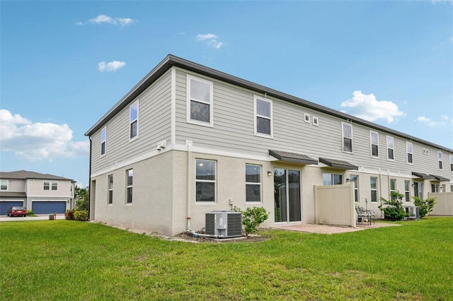 rear view of house featuring central AC, a lawn, and stucco siding