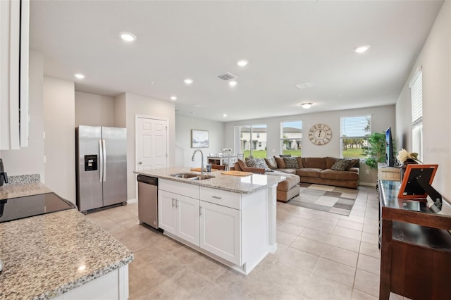 kitchen with appliances with stainless steel finishes, a sink, white cabinetry, light stone counters, and recessed lighting