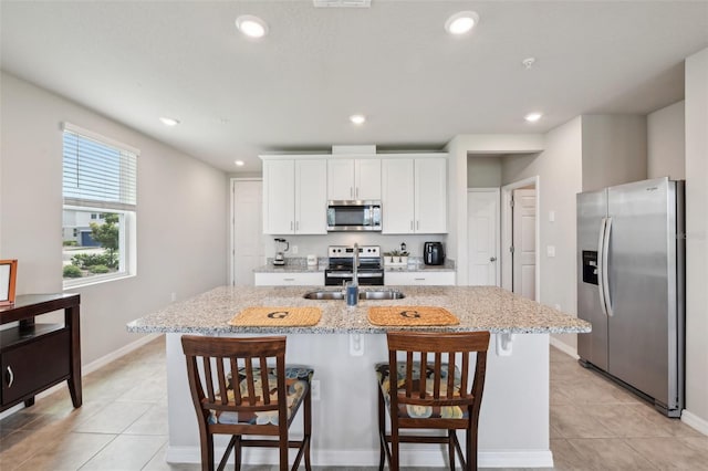 kitchen featuring stainless steel appliances, light tile patterned flooring, a breakfast bar, white cabinets, and recessed lighting