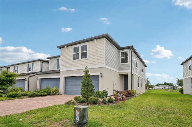 view of front of house with an attached garage, stucco siding, decorative driveway, and a front lawn