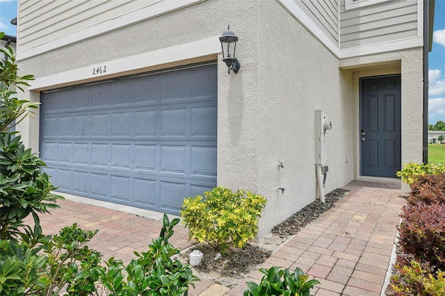 view of exterior entry featuring a garage and stucco siding