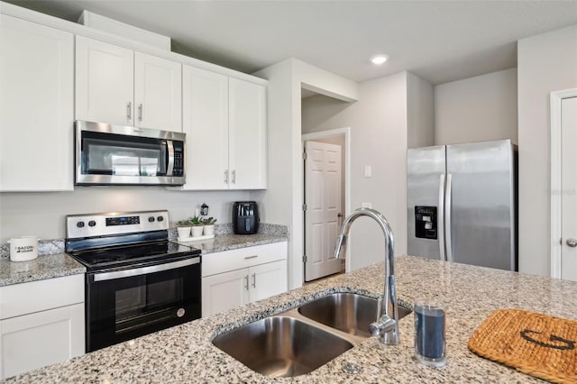 kitchen with stainless steel appliances, a sink, white cabinets, light stone counters, and recessed lighting