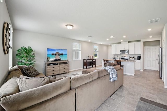 living room with light tile patterned floors, recessed lighting, and baseboards