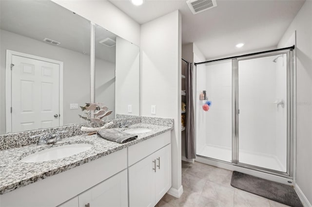 bathroom with a stall shower, double vanity, tile patterned flooring, and baseboards
