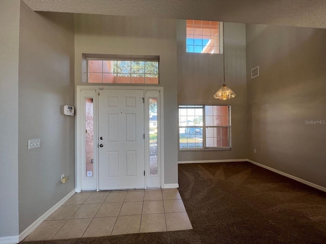 340 Cimarron Ct, Poinciana, FL 34759 - carpeted foyer entrance featuring baseboards, a towering ceiling, tile patterned floors, and a textured ceiling