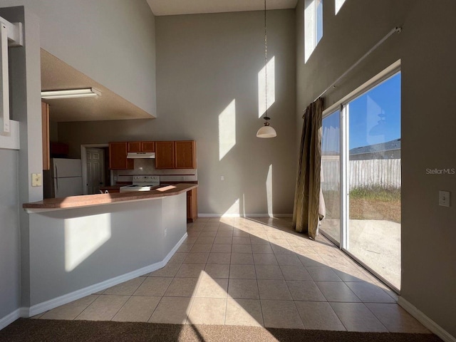 340 Cimarron Ct, Poinciana, FL 34759 - kitchen featuring white electric range oven, freestanding refrigerator, a high ceiling, under cabinet range hood, and light tile patterned floors