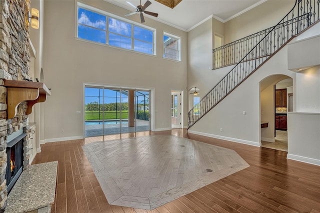 2350 Bradbury Rd, Haines City, FL 33844 - unfurnished living room featuring ornamental molding, a fireplace, ceiling fan, hardwood / wood-style flooring, and a high ceiling