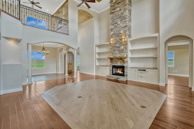 2350 Bradbury Rd, Haines City, FL 33844 - unfurnished living room featuring ceiling fan, a towering ceiling, a stone fireplace, built in shelves, and hardwood / wood-style flooring