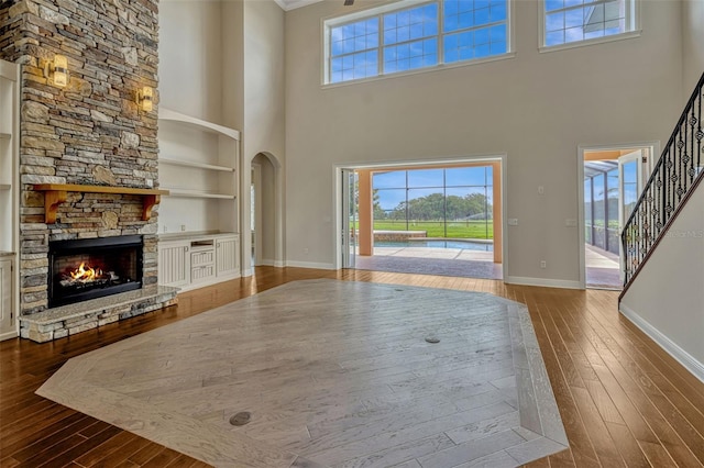 2350 Bradbury Rd, Haines City, FL 33844 - unfurnished living room with a high ceiling, baseboards, dark wood-type flooring, built in features, and a fireplace