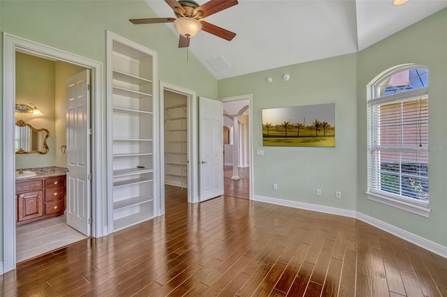 2350 Bradbury Rd, Haines City, FL 33844 - unfurnished bedroom with a walk in closet, wood finished floors, arched walkways, baseboards, and high vaulted ceiling