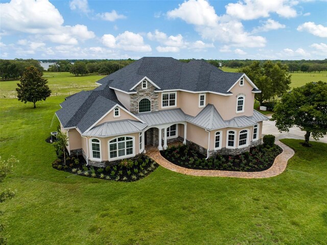 2350 Bradbury Rd, Haines City, FL 33844 - view of front of home with a standing seam roof, stone siding, stucco siding, and a front lawn
